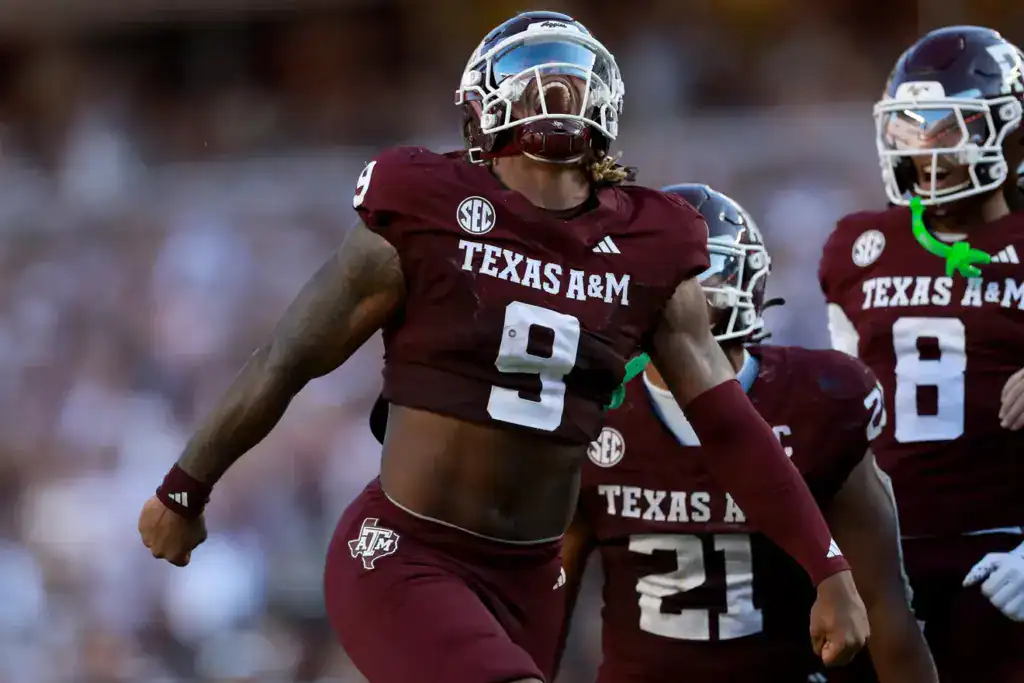 Cashius Howell draft prospect celebrates a big play for Texas A&M, wearing No. 9 in a maroon uniform with teammates behind him.