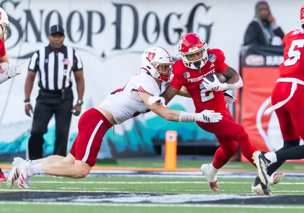 2026 NFL Draft prospect Jackson Kuwatch of Miami (Ohio) wraps up Fresno State running back Malik Sherrod during a game, diving low for a tackle as Sherrod tries to cut upfield.