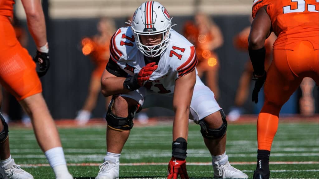 Caleb Lomu, Utah draft prospect, lined up at the line of scrimmage in a white Utes uniform before the snap.