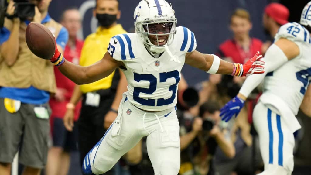 Kenny Moore II celebrates after a big play for the Indianapolis Colts, holding the football out wide in a white road uniform.