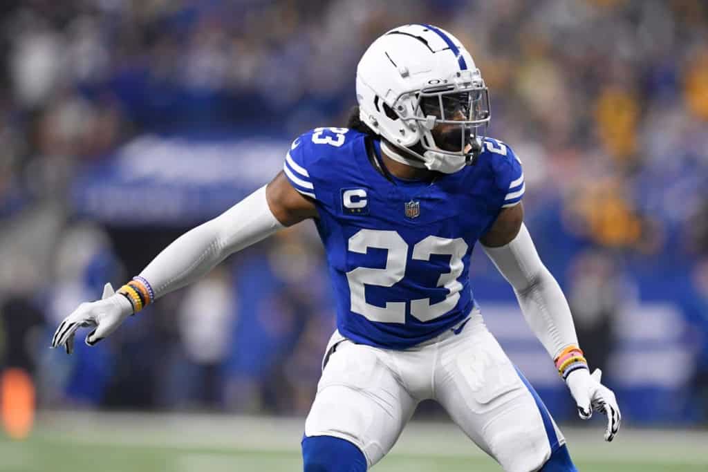 Colts cornerback Kenny Moore II lines up before the snap in a blue home jersey, ready in coverage with the crowd blurred behind him.