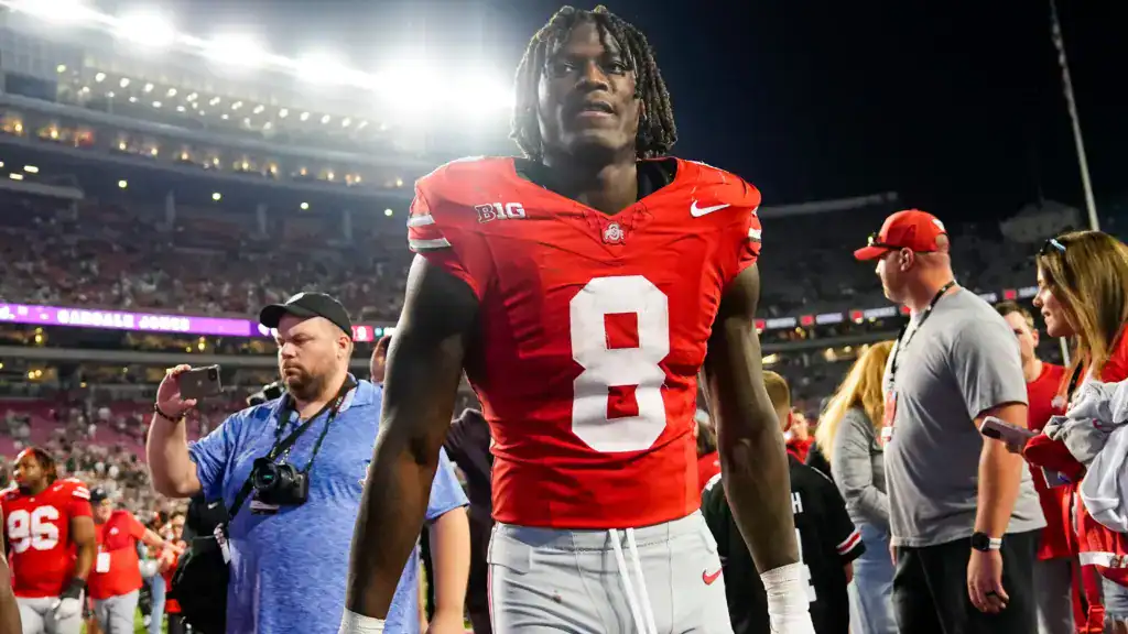Arvell Reese of Ohio State in a red No. 8 uniform standing on the sideline under stadium lights after the game.