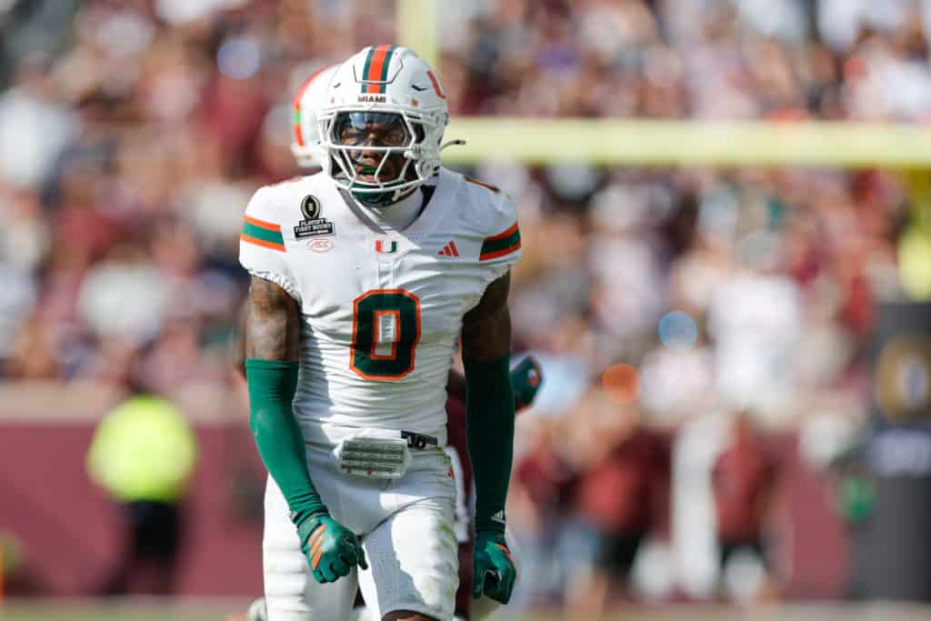 Keionte Scott, Miami defensive back and 2026 NFL Draft prospect, stands on the field in a white Hurricanes uniform during game action.