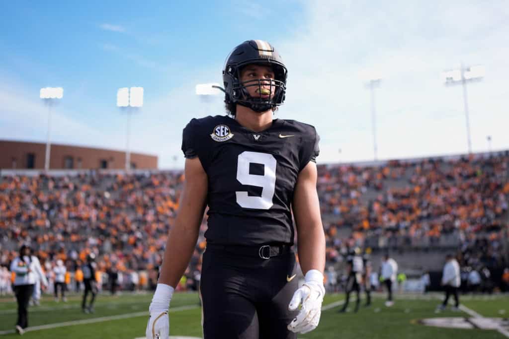 Top-30 visitor Eli Stowers in a Vanderbilt black uniform standing on the field during warmups.