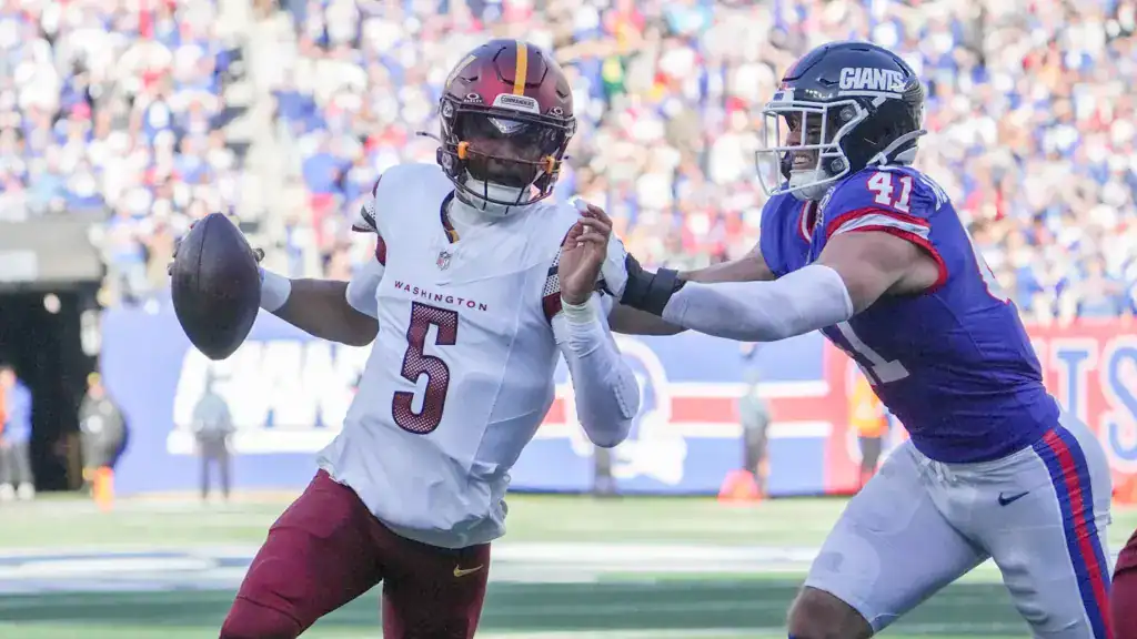 Jayden Daniels rolls out under pressure from a New York Giants defender during a Washington Commanders game, representing Washington in an NFC East betting odds.
