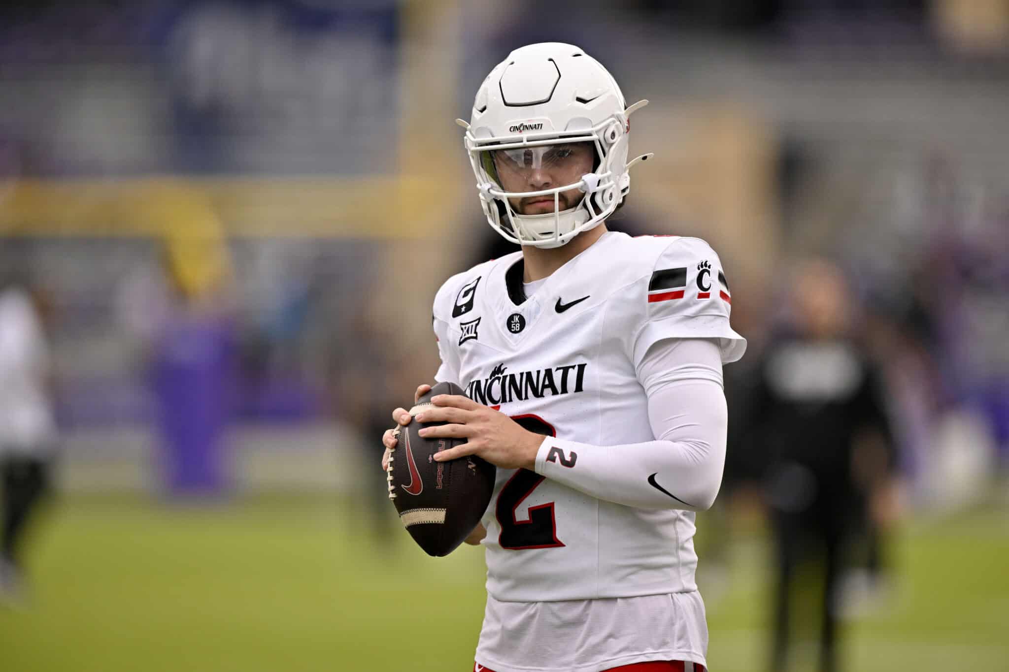 Brendan Sorsby holding the football in a white Cincinnati Bearcats uniform before making a throw