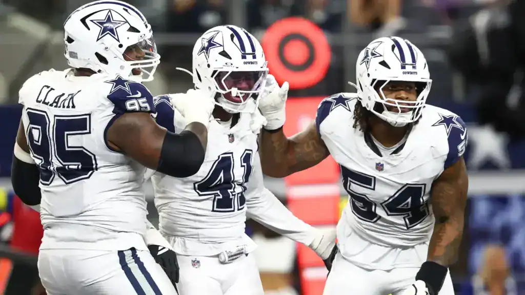 Dallas Cowboys defense celebrating during a game with players in white uniforms.
