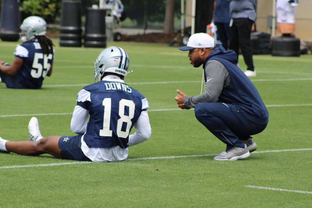 Dallas Cowboys rookie safety Caleb Downs talks with a coach Christian Parker during practice, adding aweapon to the defense in the Cowboys’ 2026 record prediction discussion.