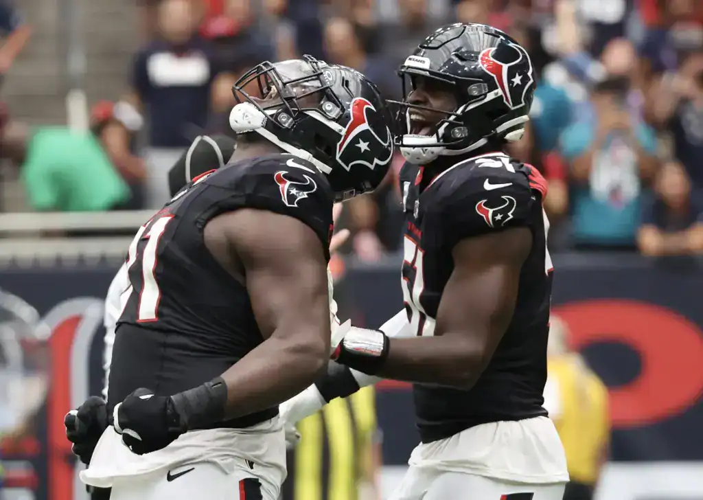 Veteran free agent defensive tackle Folorunso Fatukasi celebrates with a teammate while wearing a Houston Texans uniform.