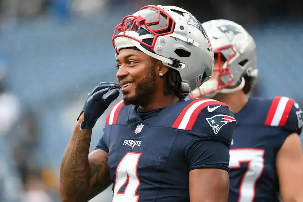 Veteran free agent running back Antonio Gibson smiles on the field while wearing a New England Patriots uniform.