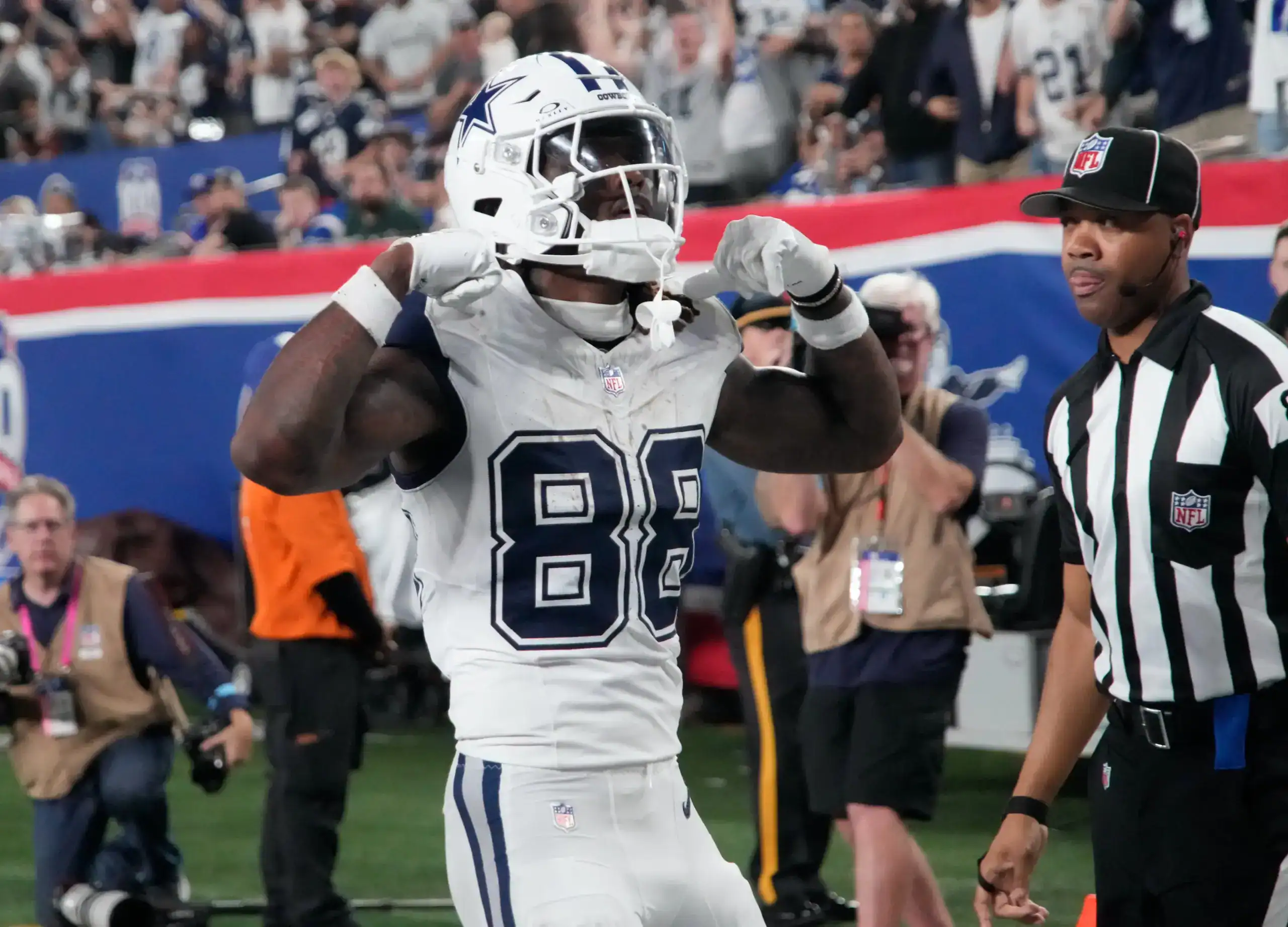 CeeDee Lamb flexing after scoring for the Dallas Cowboys in a white road uniform.