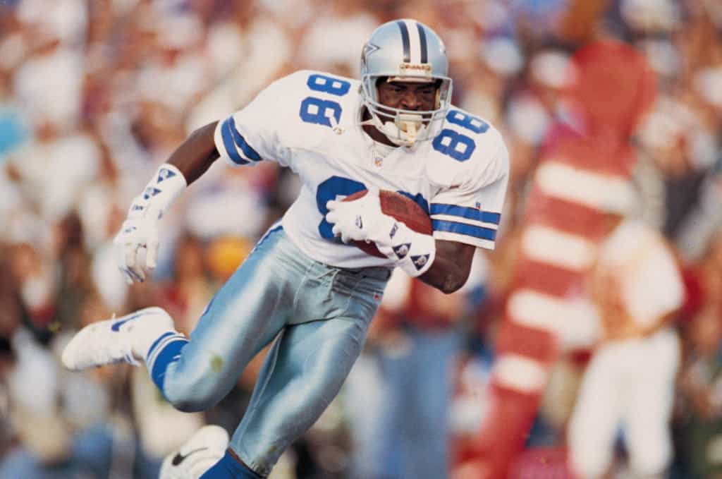 CeeDee Lamb is Chasing Cowboys History in 2026 Michael Irvin carrying the football in a classic Dallas Cowboys road uniform during game action.