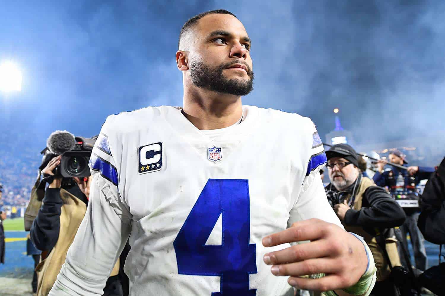 Dallas Cowboys quartebcak Dak Prescott walking off the field being followed by media