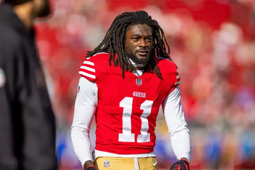 Brandon Aiyuk to Dallas Sounds Good Until The Headache Takes Over Brandon Aiyuk stands on the field in his red San Francisco 49ers No. 11 uniform.
