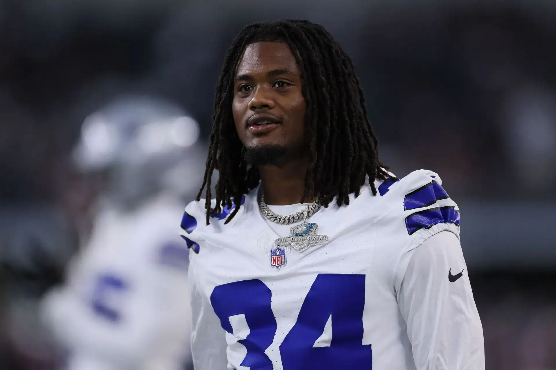 Jaydon Blue stands on the sideline in a Dallas Cowboys No. 34 jersey before a game.