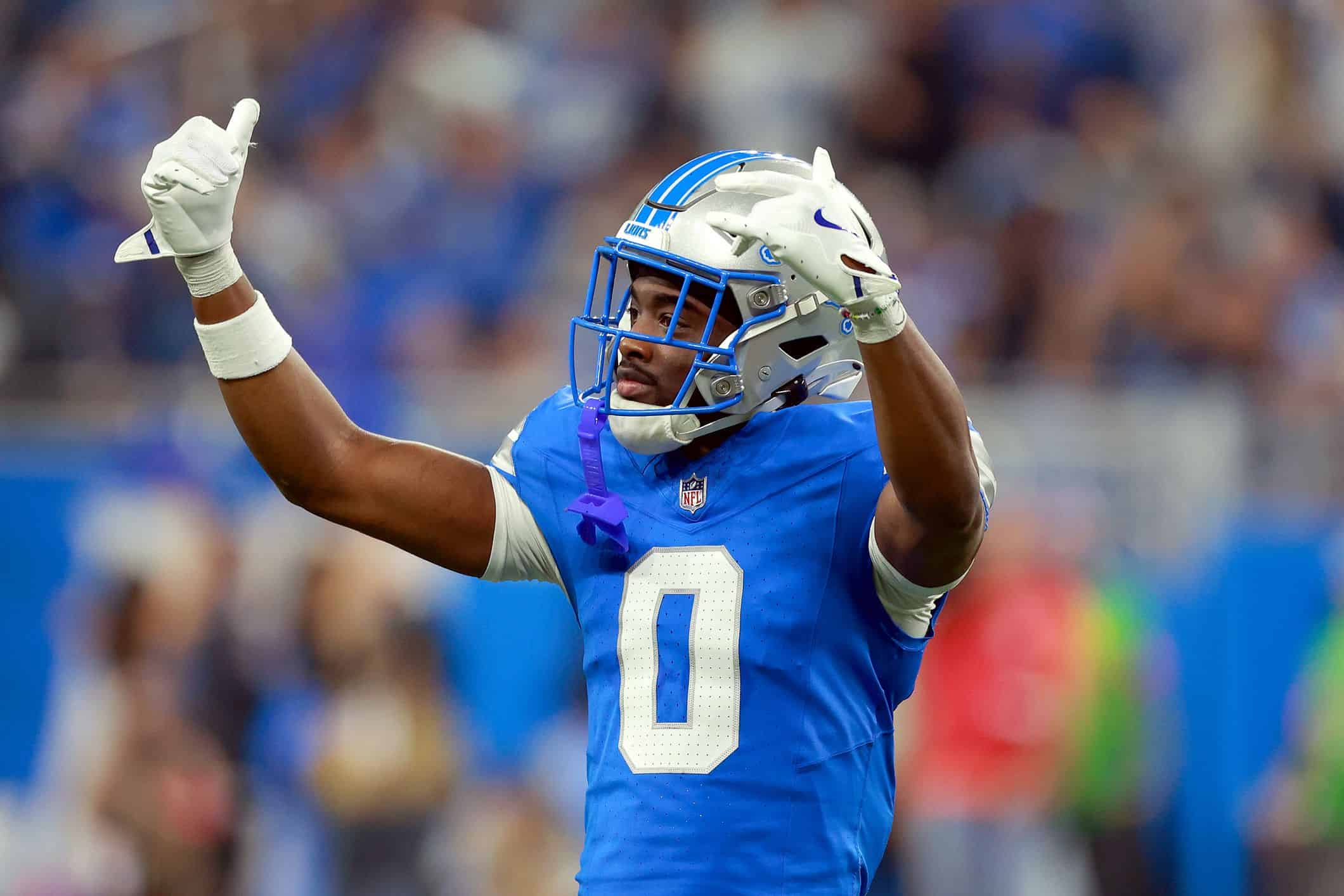 Terrion Arnold celebrates in a Detroit Lions uniform with both arms raised during a game.