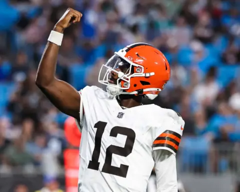 Shedeur Sanders celebrates with a raised fist while wearing his white Cleveland Browns No. 12 jersey.