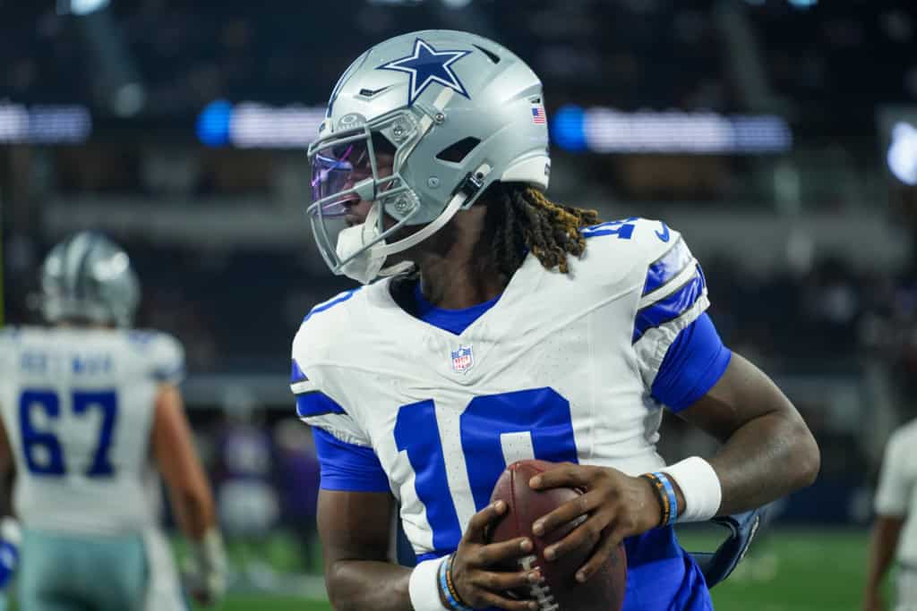 Joe Milton holds a football while warming up in a Dallas Cowboys uniform.