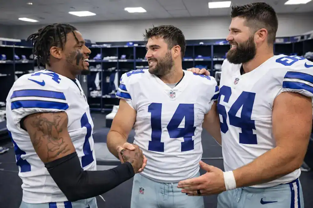Sam Howell talks with Dallas Cowboys teammates inside the locker room.