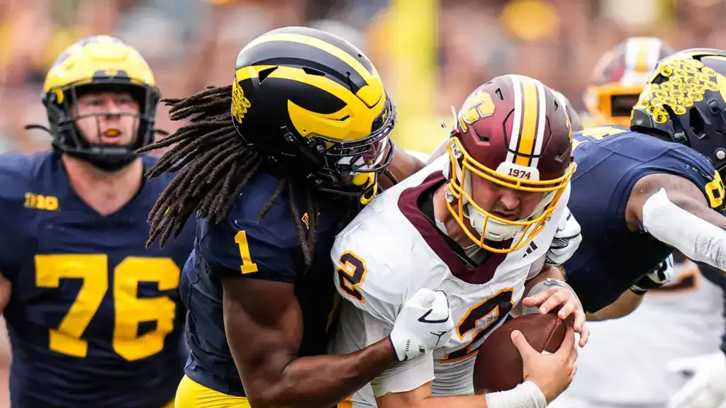 Michigan linebacker Jaishawn Barham delivers a hard tackle against Central Michigan quarterback during a college football game.