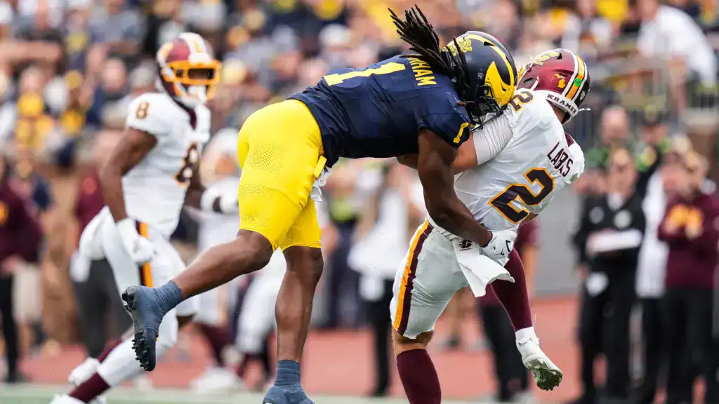 Michigan linebacker Jaishawn Barham tackles a Central Michigan ball carrier during a college football game.