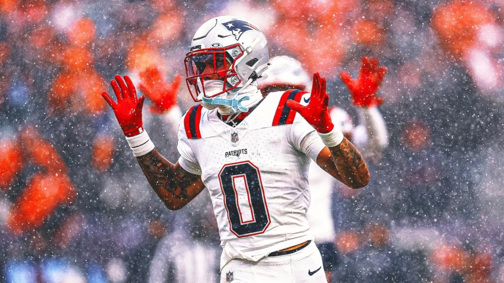 Maxx Crosby vs Christian Gonzalez: A Cowboys Bet? New England Patriots cornerback Christian Gonzalez in a white No. 0 uniform raises his hands on the field during a snowy NFL game.