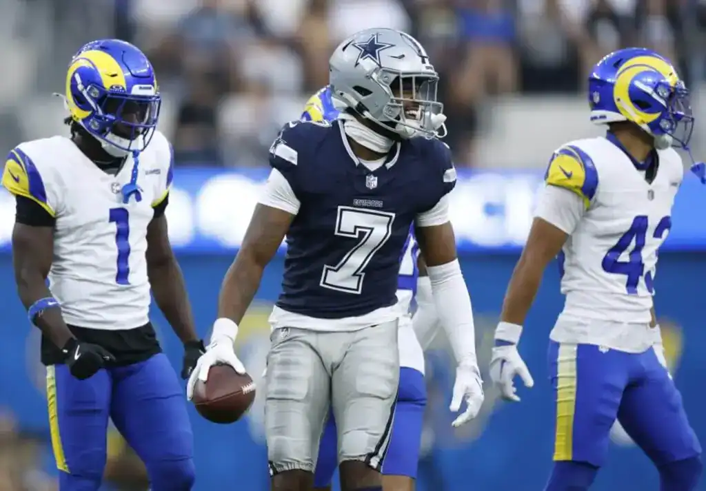 Dallas Pass Catchers Make Their Case in Preseason Game 1 Traeshon Holden holds the football after a play while surrounded by Los Angeles Rams defenders during a preseason game.