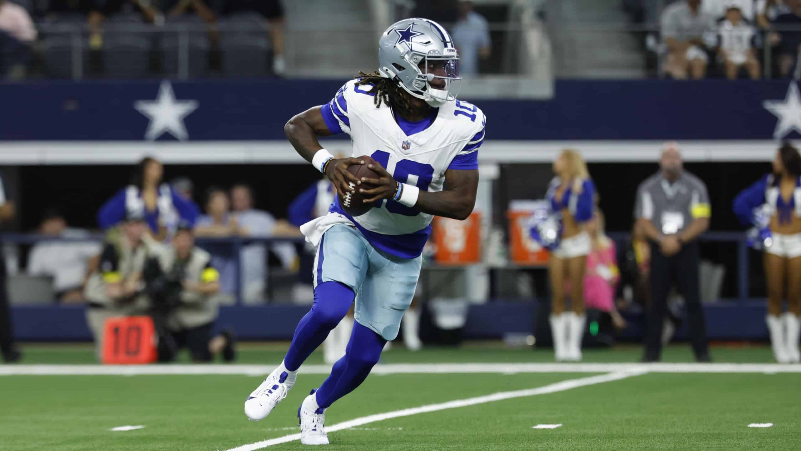 Dallas Cowboys player Joe Milton rolls out with the football during a preseason game.