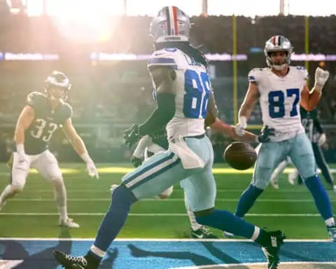 CeeDee Lamb drops a pass near the end zone during a Dallas Cowboys game as teammates and defenders look on.