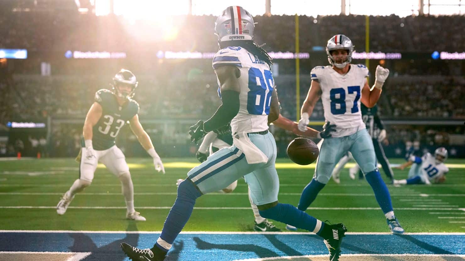 CeeDee Lamb drops a pass near the end zone during a Dallas Cowboys game as teammates and defenders look on.