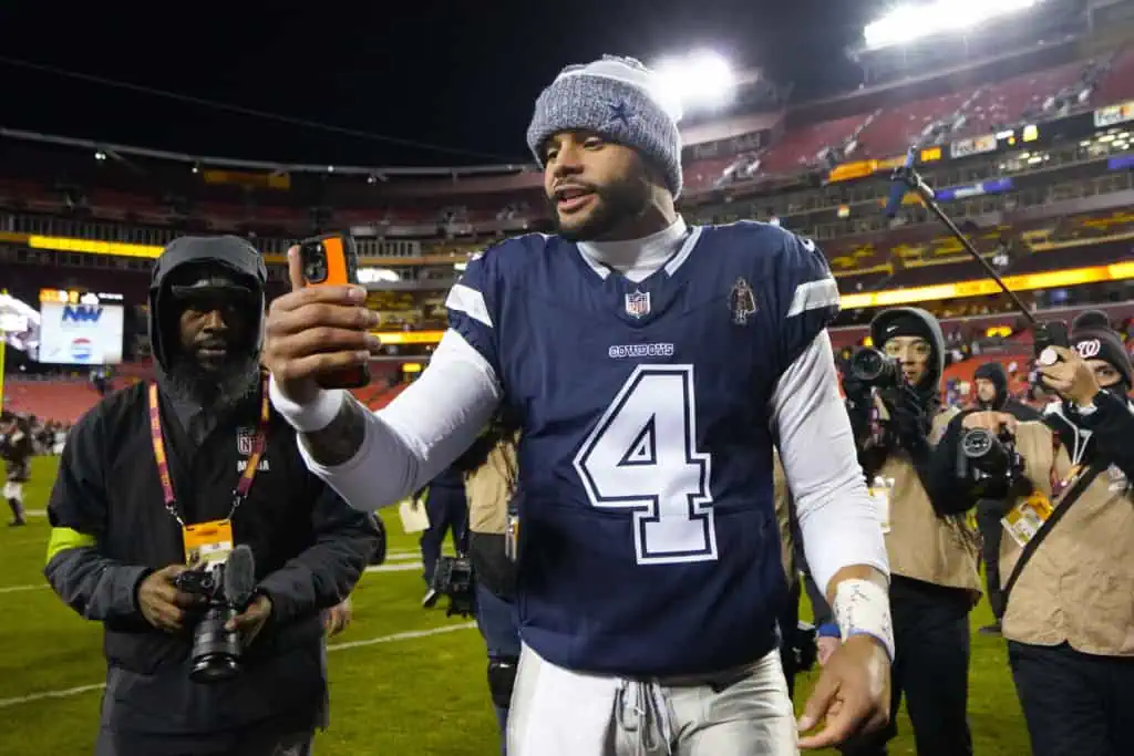 Dallas Cowboys quarterback Dak Prescott (4) using a phone as he heads off the field at the end of an NFL football game against the Washington Commanders, Sunday, Jan. 7, 2024, in Landover, Md. Dallas won 38-10. (AP Photo/Jessica Rapfogel)