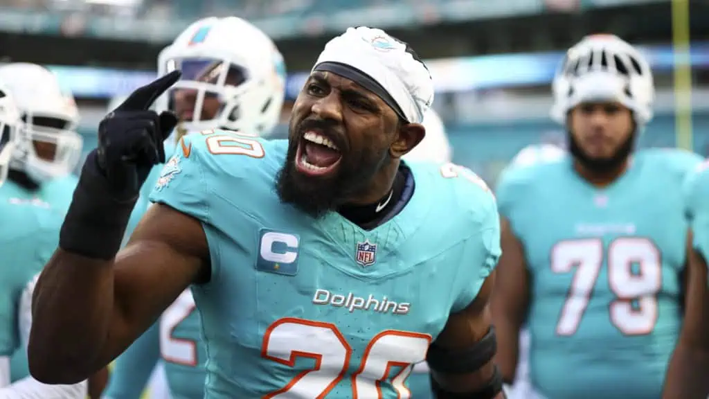 Jordyn Brooks gestures toward his head while speaking to teammates on the Miami Dolphins sideline.