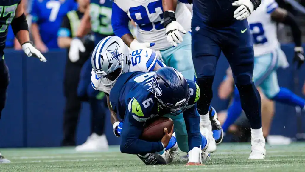Dallas Cowboys defender Isaiah Land tackles the Seattle Seahawks quarterback during a preseason game.