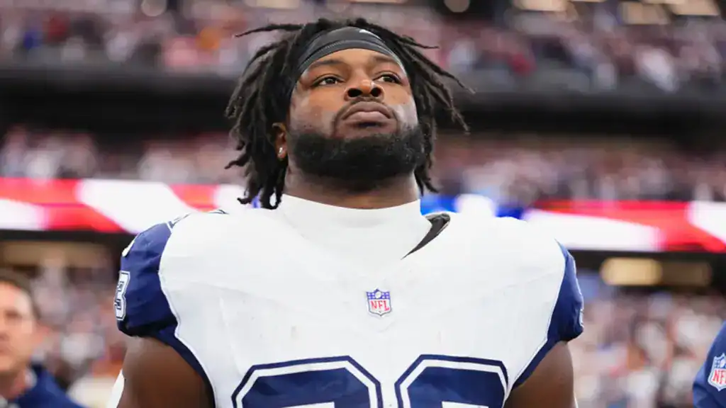 Dallas Cowboys running back Javonte Williams standing on the sideline before a game staring off onto the field.
