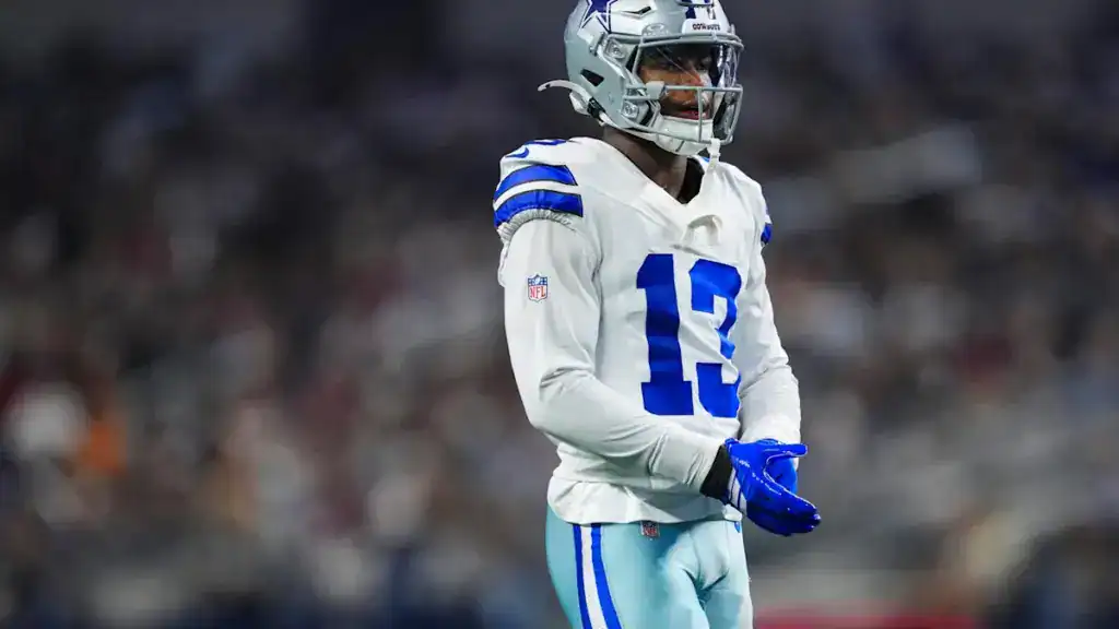Cowboys rookie safety Caleb Downs in a white Dallas Cowboys uniform adjusting his blue gloves. 