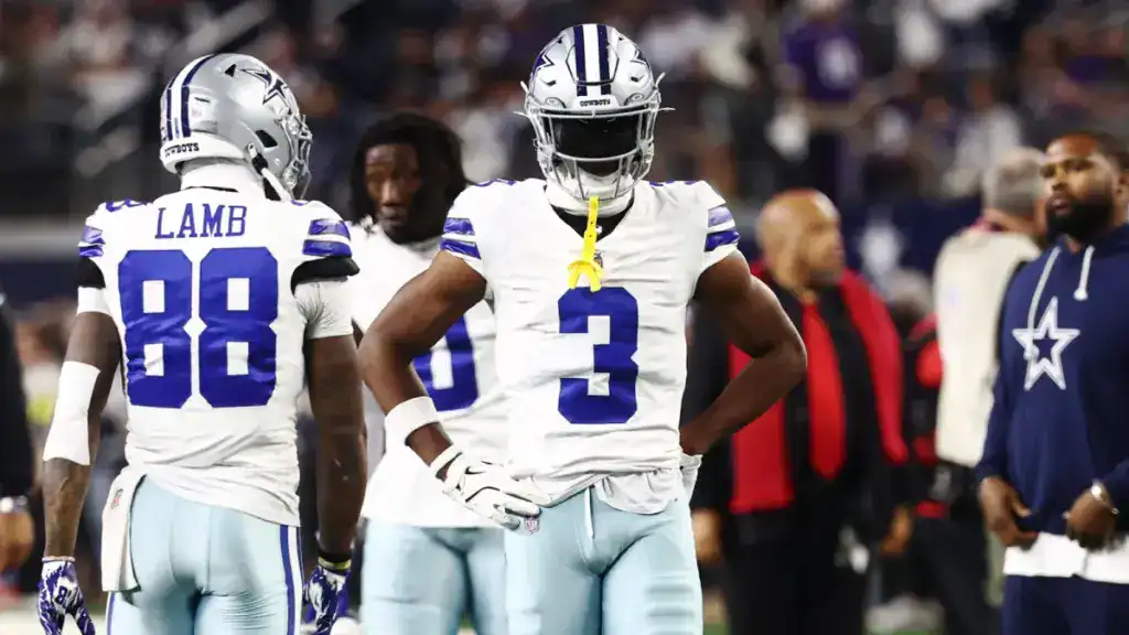 Cowboys wide receiver George Pickens standing in front of CeeDee Lamb both wearing white jerseys.