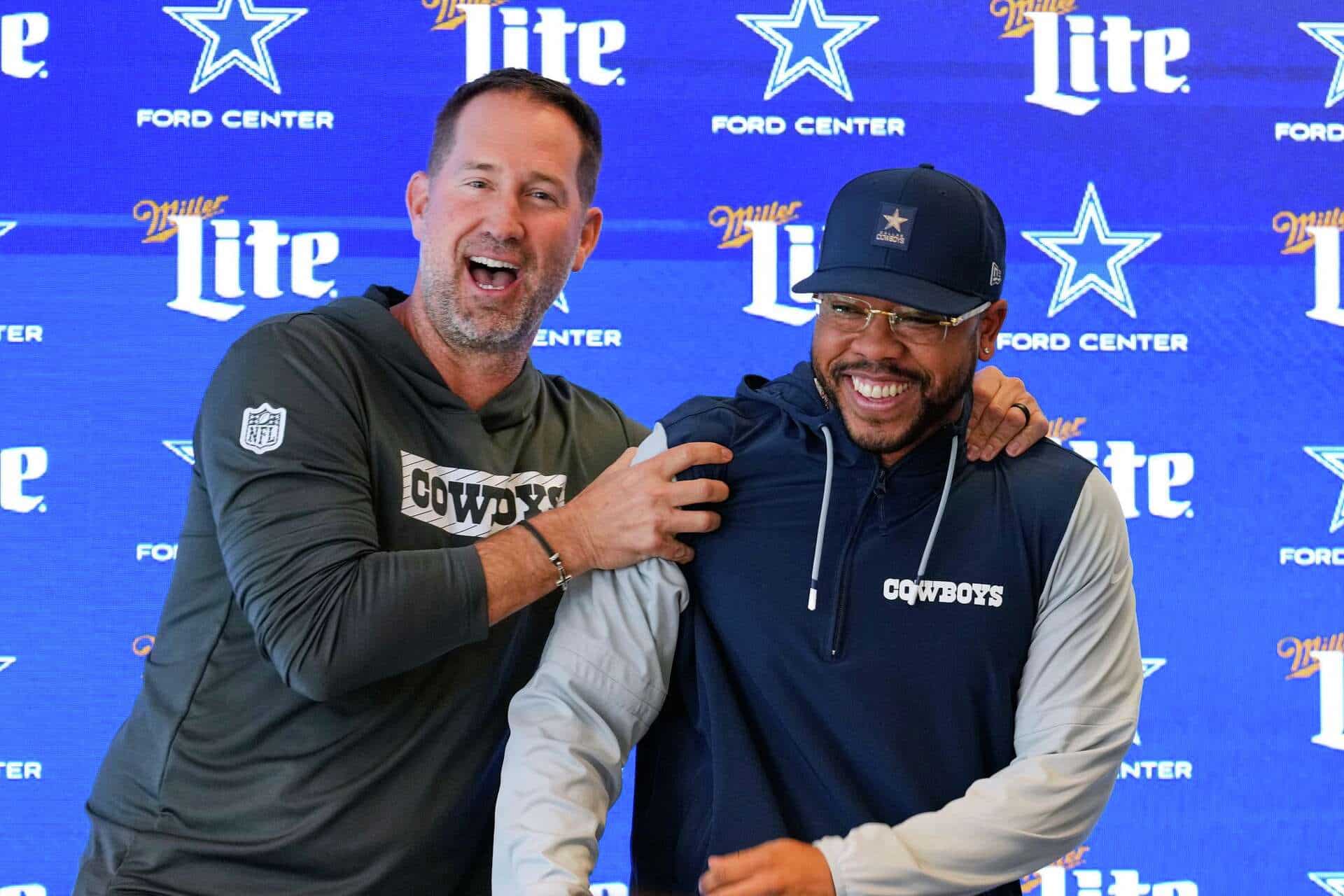 Dallas Cowboys coaches Christian Parker and Brian Schottenheimer laughing during Parker's introductory press conference.