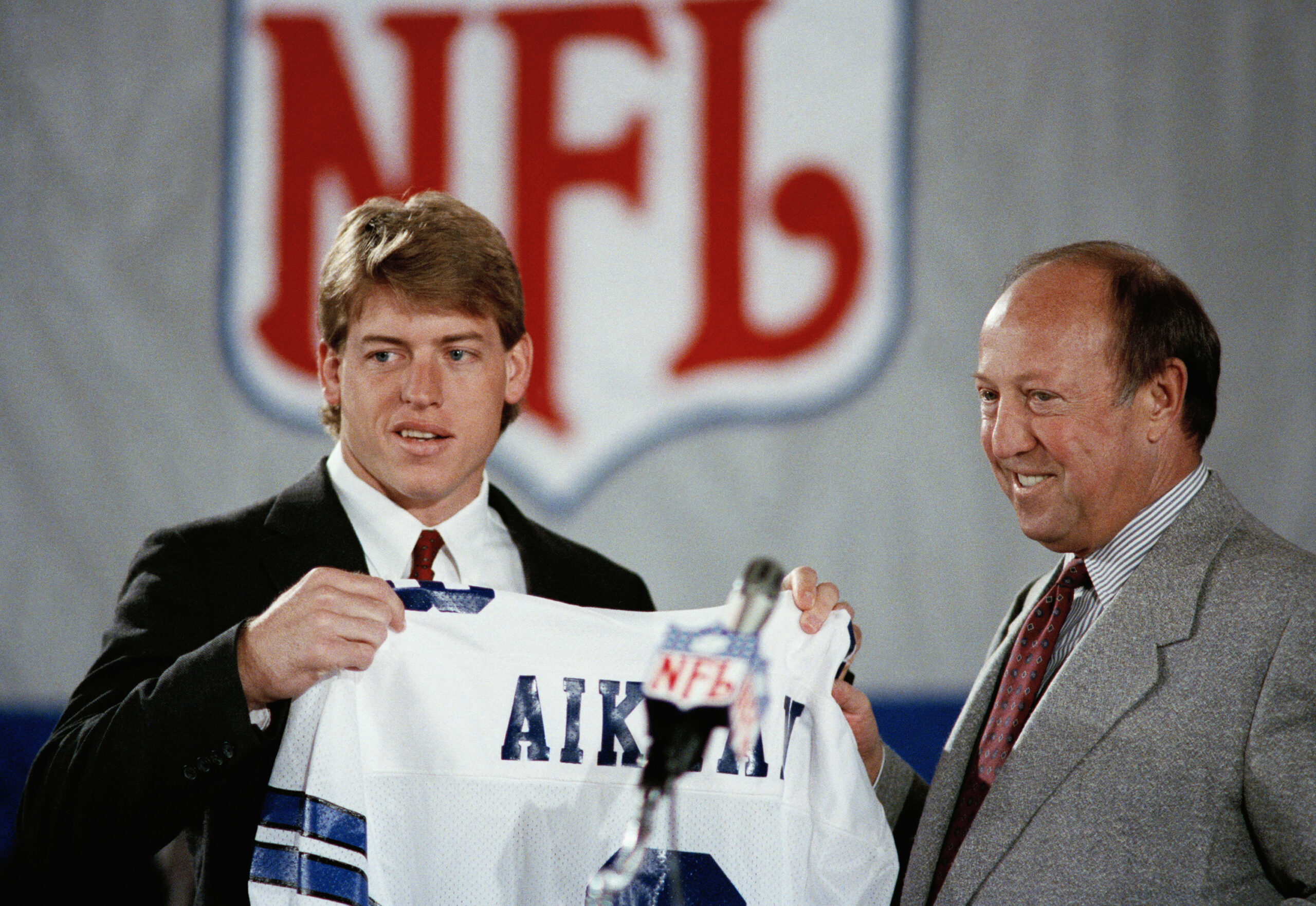 Pete Rozelle, NFL commissioner, right, began the 54th annual draft of collegiate talent. His final draft, by announcing the selection of UCLA quarterback Troy Aikman left, as the first pick by the Dallas Cowboys on Sunday, April 23, 1989 in New York. Aikman already has signed a six-year, $11.2 million contract wih the Cowboys.(AP Photo/Mark Lennihan) ORG XMIT: APHS120414