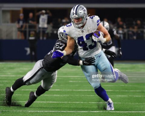 In a thrilling preseason match, the football player in a blue and white jersey dashed across the field with determination, only to be expertly tackled by his opponent in a black and silver jersey.