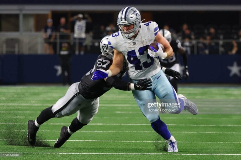 In a thrilling preseason match, the football player in a blue and white jersey dashed across the field with determination, only to be expertly tackled by his opponent in a black and silver jersey.