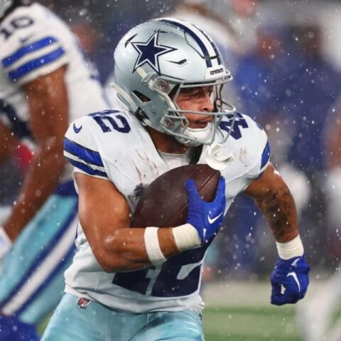 Cowboys' Deuce Vaughn, dressed in a white and blue uniform, sprints with the ball during a game.