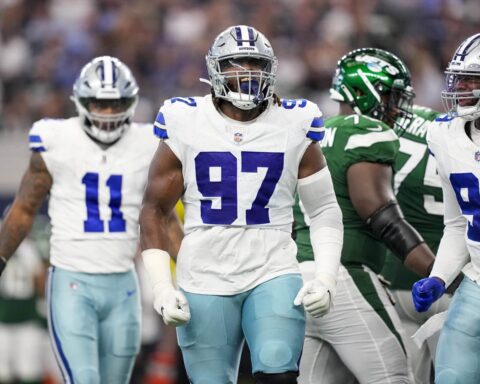 Football players from the Cowboys and Jets during a game, with a focus on a Cowboy wearing jersey number 97.