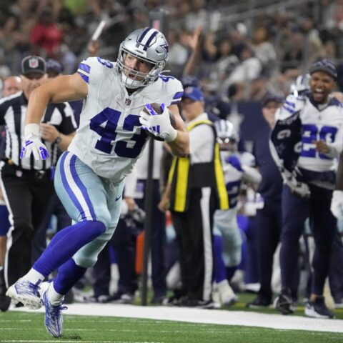 Hunter Luepke, in his Cowboys uniform, charges down the field with the ball, while both teammates and 49ers opponents focus on every move.