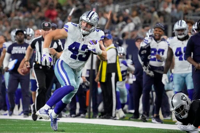 Hunter Luepke, in his Cowboys uniform, charges down the field with the ball, while both teammates and 49ers opponents focus on every move.