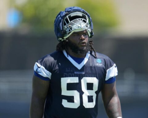 Football player in navy and white gear and helmet, numbered 58, stands on the field with a focused expression.