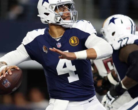 Football player in a blue and white uniform preparing to throw a pass during a game.