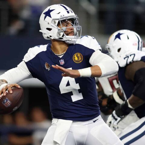 Football player in a blue and white uniform preparing to throw a pass during a game.