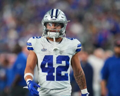 Football player in a white and blue uniform with number 42 walking on the field.