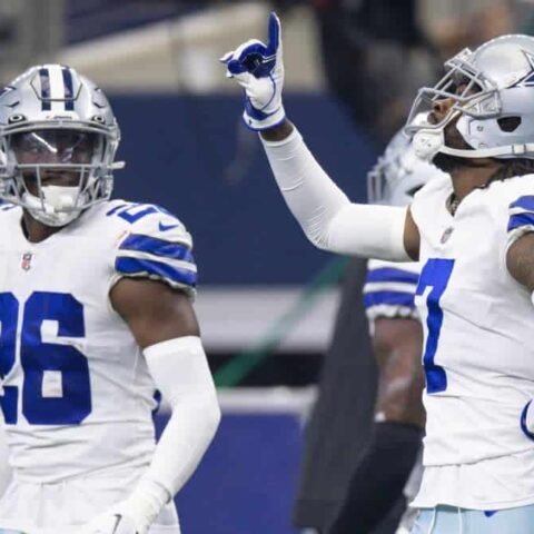 Two football players in Dallas Cowboys uniforms, including cornerback DaRon Bland, with one pointing upwards during a game.