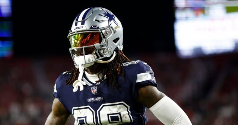 Football player in a Dallas Cowboys uniform and helmet stands on the field during a game.